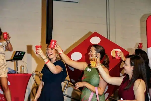 People celebrating with red cups at CURE Childhood Cancer event.