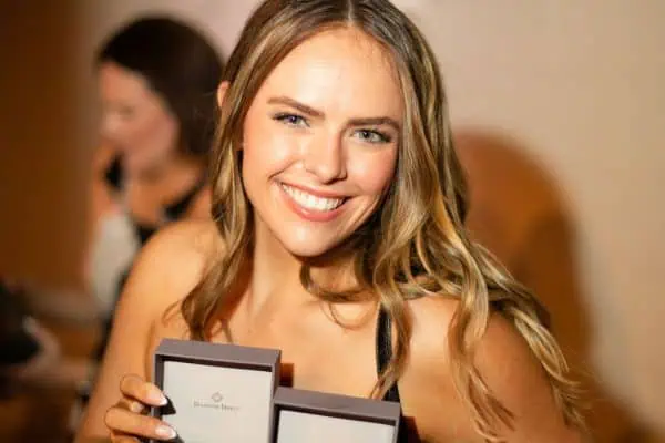 Smiling woman holding award boxes at CURE Childhood Cancer event.