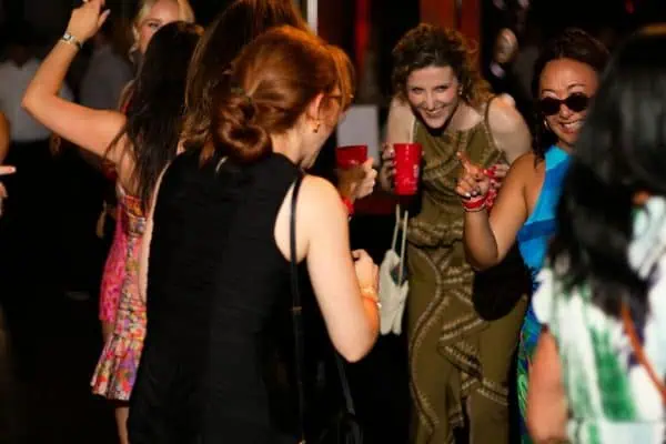 Group of women celebrating at a CURE Childhood Cancer event with drinks and smiles.
