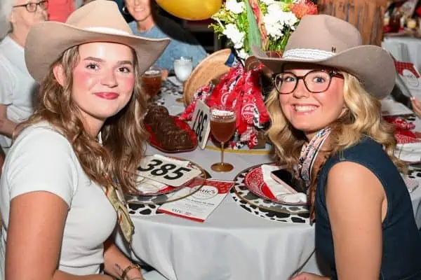 Two women wearing cowboy hats at CURE Childhood Cancer event.