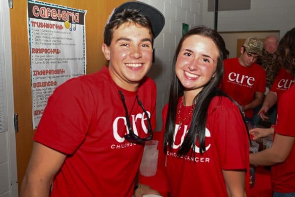 Smiling young man and woman wearing CURE T-shirts at charity event.