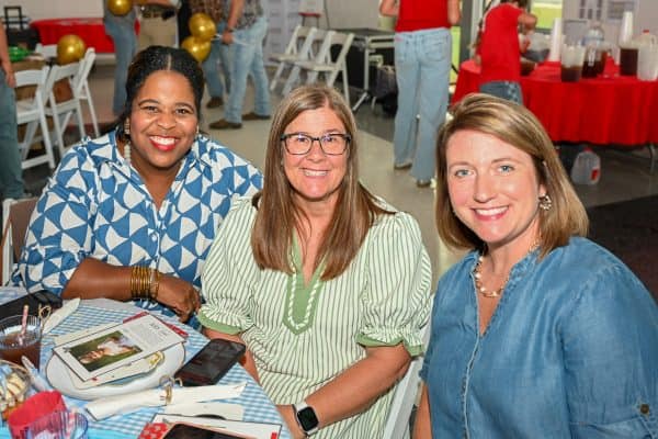 Three women smiling at CURE Childhood Cancer gathering event.