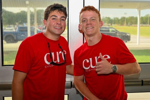 Two young men in red CURE shirts smiling at the event.