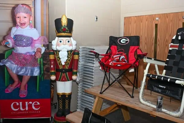 Child at CURE Childhood Cancer event with festive decorations and chairs.