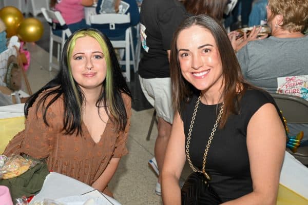 Two smiling women at CURE Childhood Cancer gathering event.