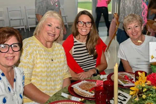 Group of women smiling at CURE Childhood Cancer event table.