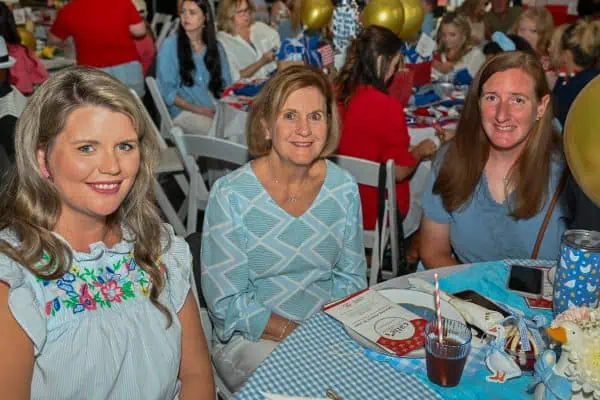 Women enjoying CURE Childhood Cancer fundraising event with decorations and attendees.